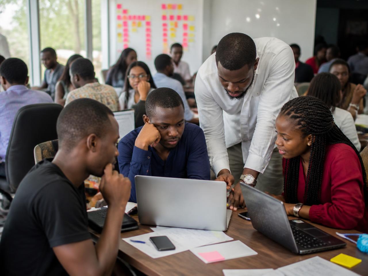 Founders working on laptops with a coach during an accelerator workshop