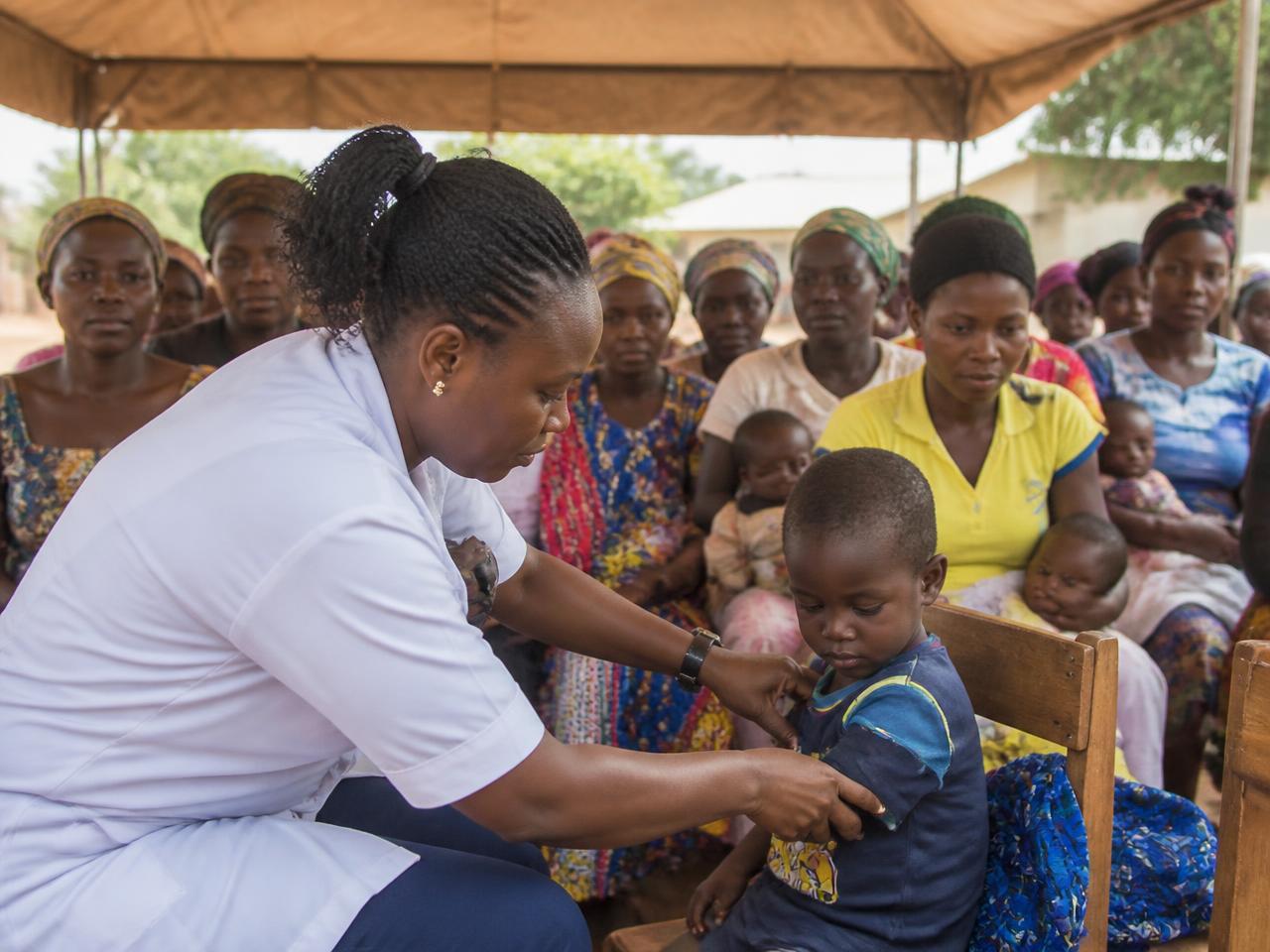 A nurse attending to a child at a community health outreach