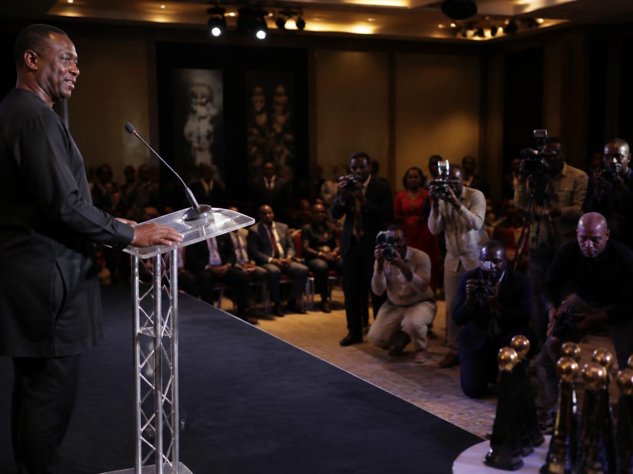 A speaker addressing press and guests at an awards event